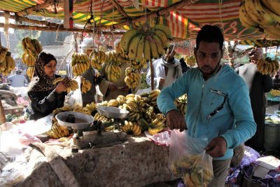 Bananenstand auf Markt mit Haendler und Kundin