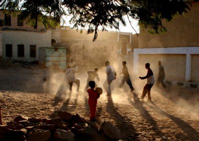 Kinder spielen Fußball auf staubigem Platz