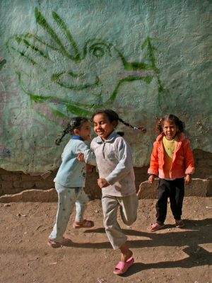 Kinder tanzen vor einer Wand mit gemalter Friedenstaube