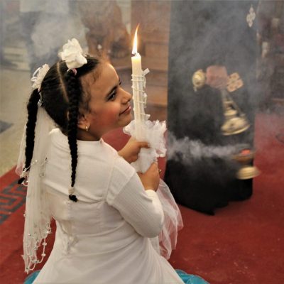 Frau mit Kerze neben Priester