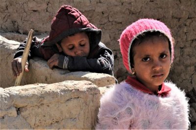 zwei Kinder neben Lehmmauer