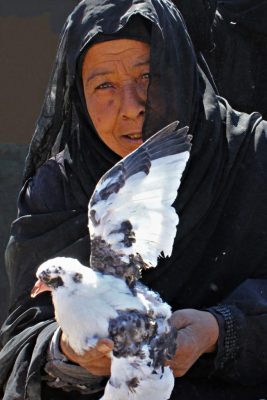 Frau in schwarz hält eine Taube