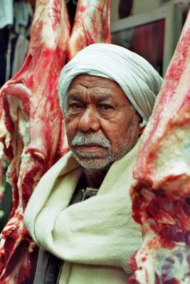 Fleischer steht zwischen großen Fleischstücken